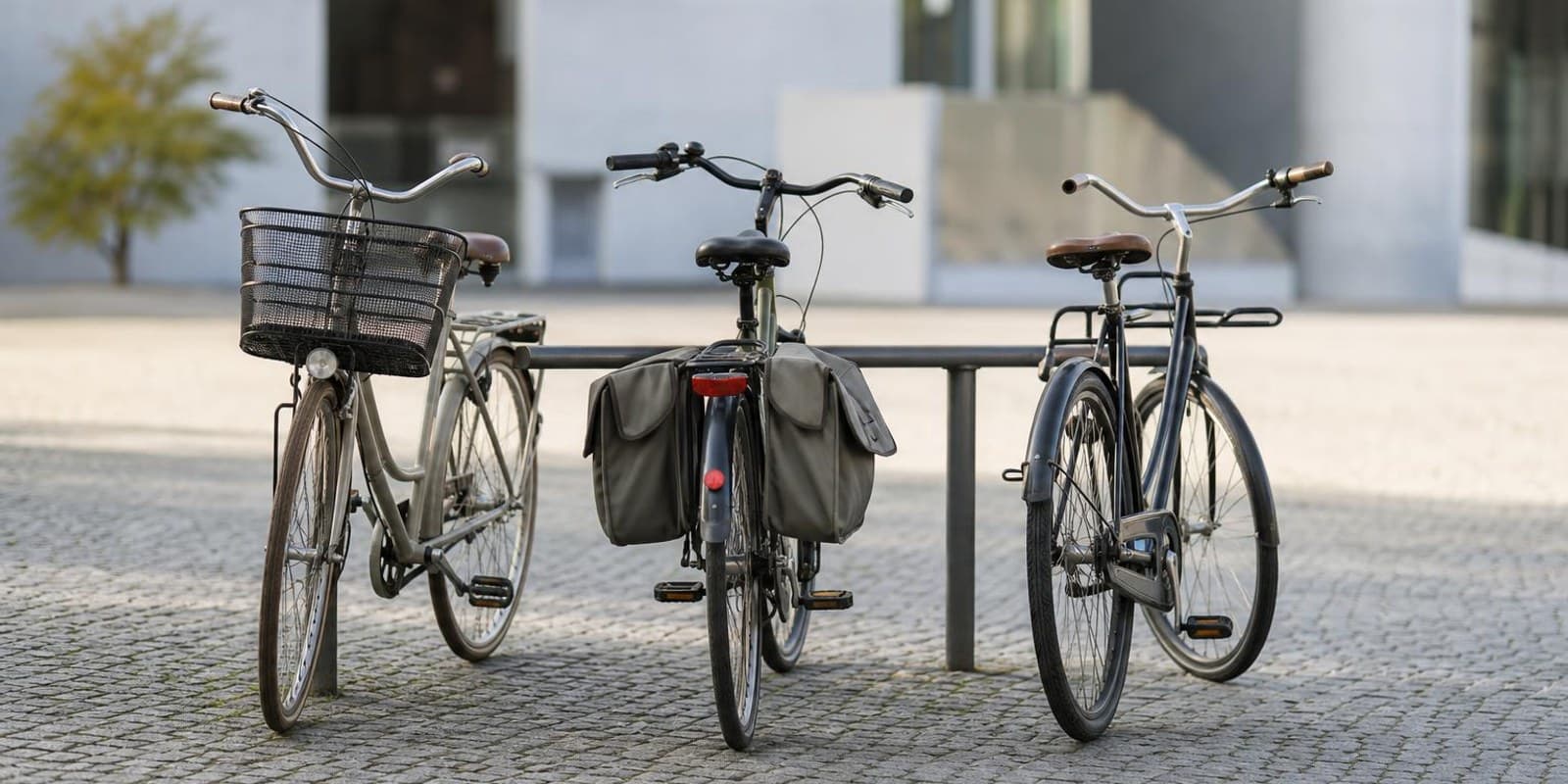 Drei unterschiedliche Alltagsraeder stehen nebeneinander am Fahrradstaender auf einem Platz.