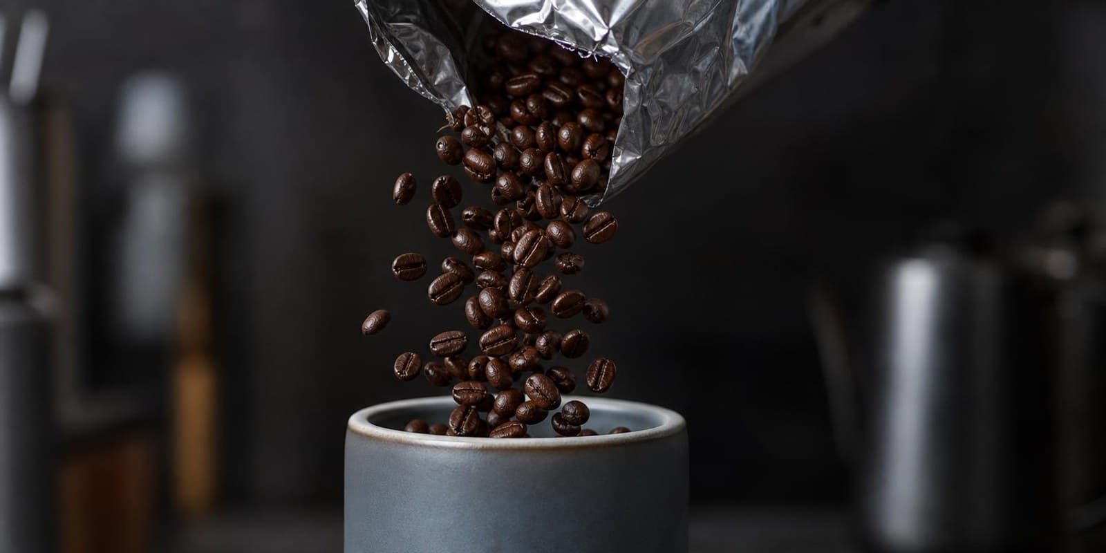 Kaffeebohnen fallen aus einem Beutel in eine Keramikdose mit Dichtungsdeckel.