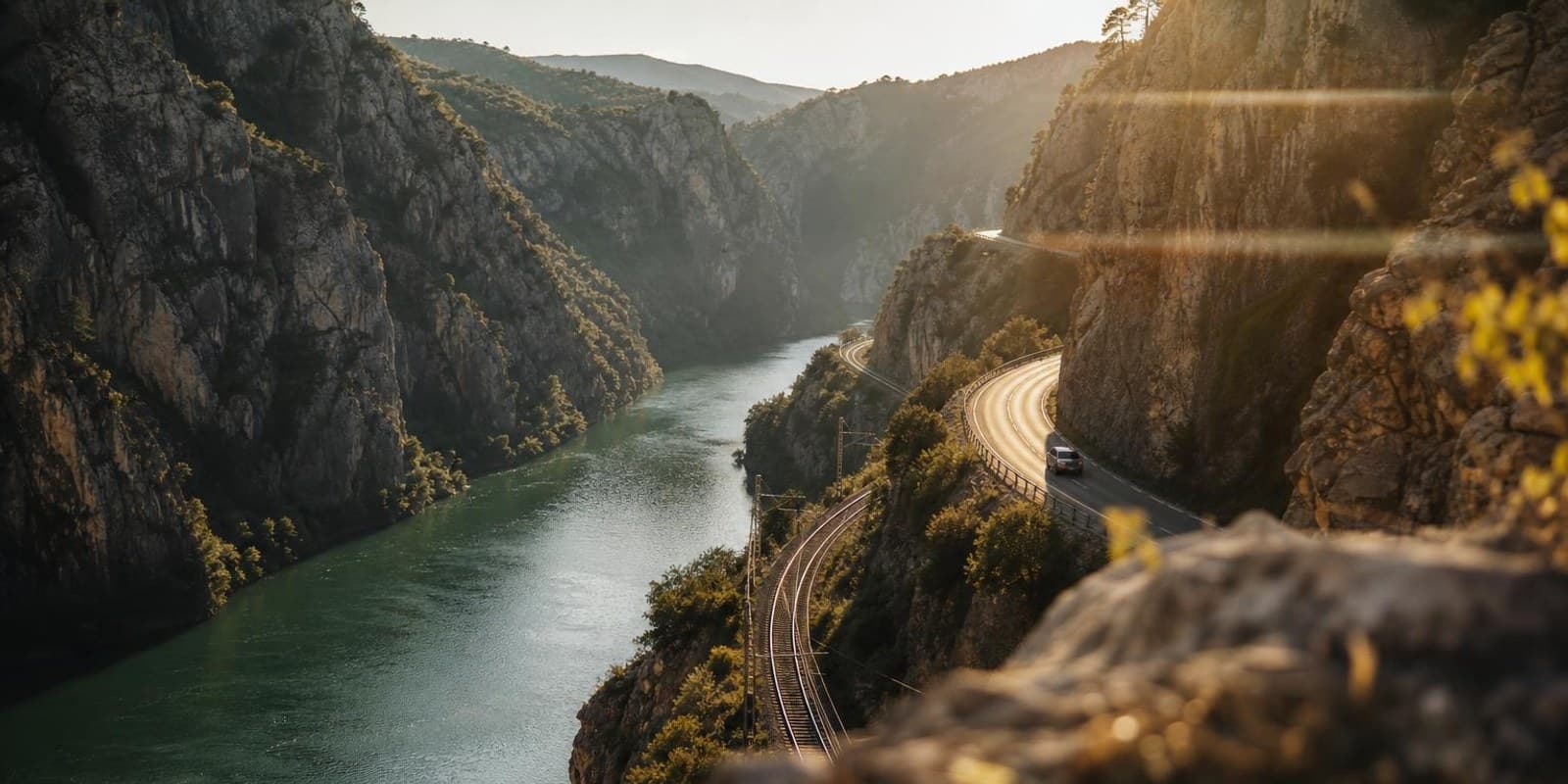 Die smaragdgruene Neretva schlaengelt sich durch eine felsige Schlucht, Strasse und Bahnlinie folgen ihr.
