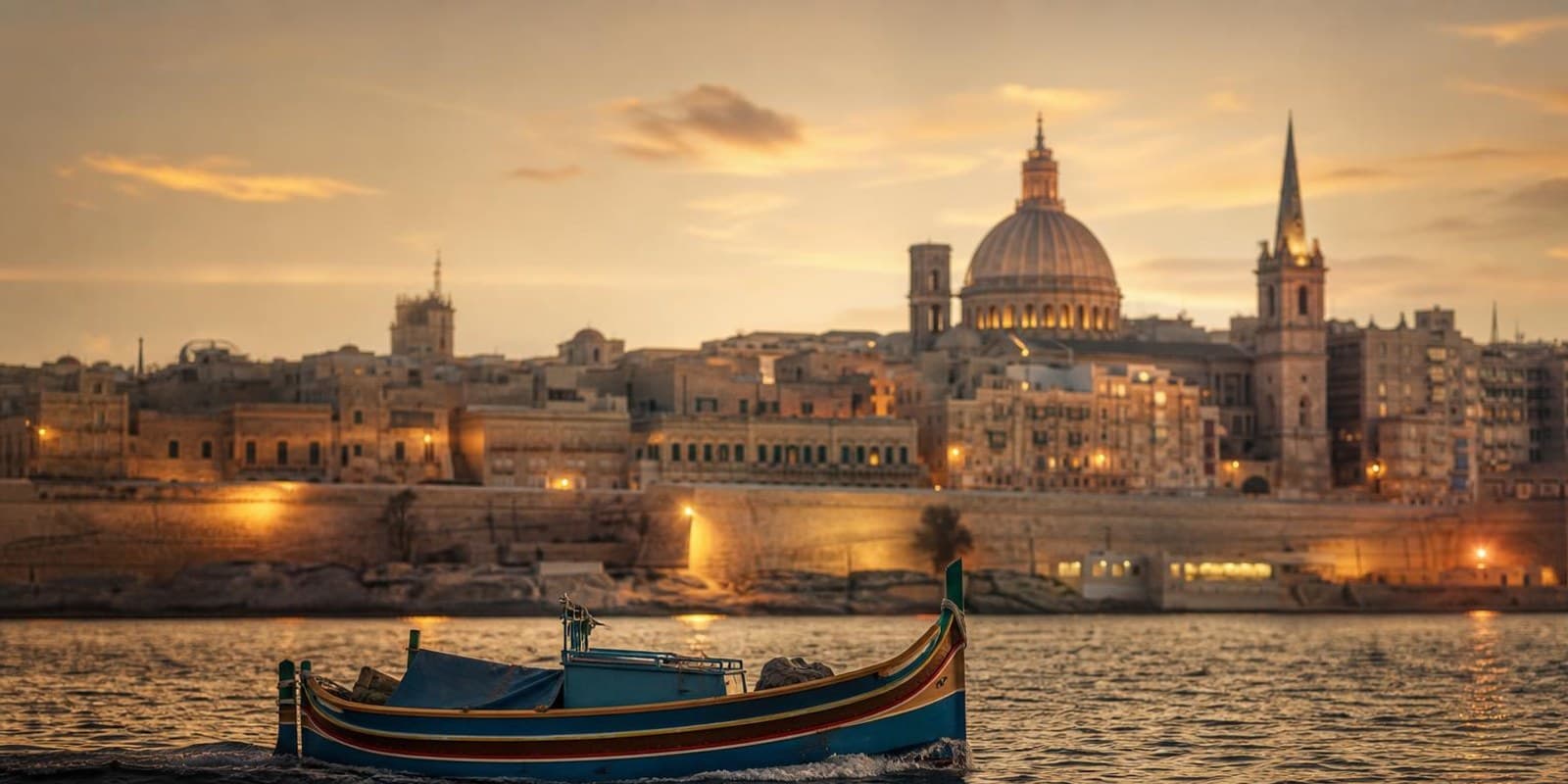 Festungsstadt Valletta leuchtet abends golden ueber dem Grand Harbour.