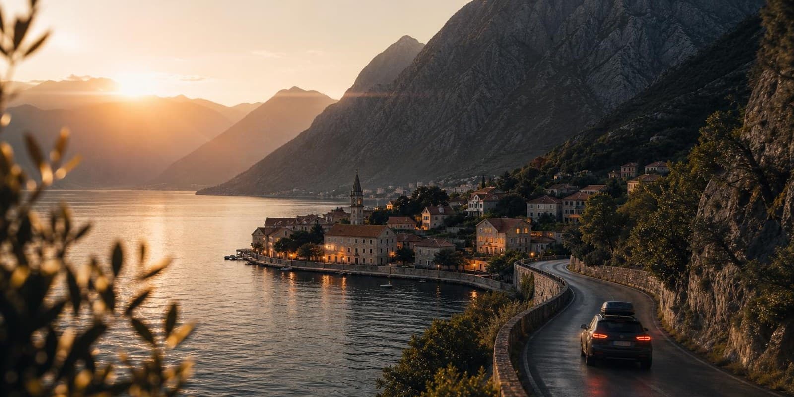 Kuestenstrasse ueber der Bucht von Kotor mit Steinort auf einer Halbinsel im Abendlicht.