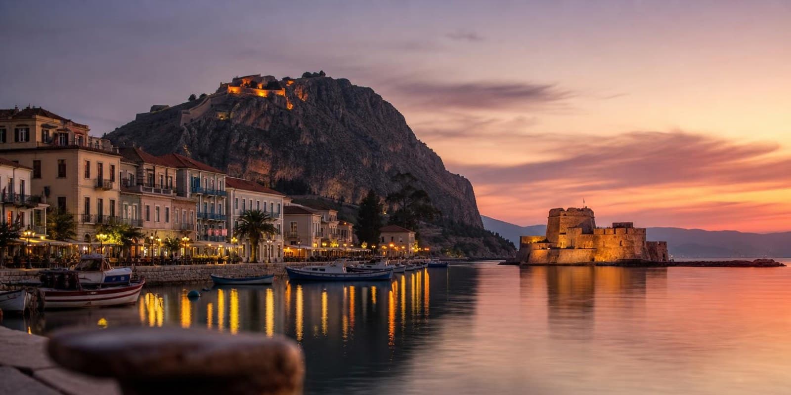 Abendstimmung im Hafen von Nafplio mit der kleinen Festungsinsel im Wasser und der Burg auf dem Felsen.
