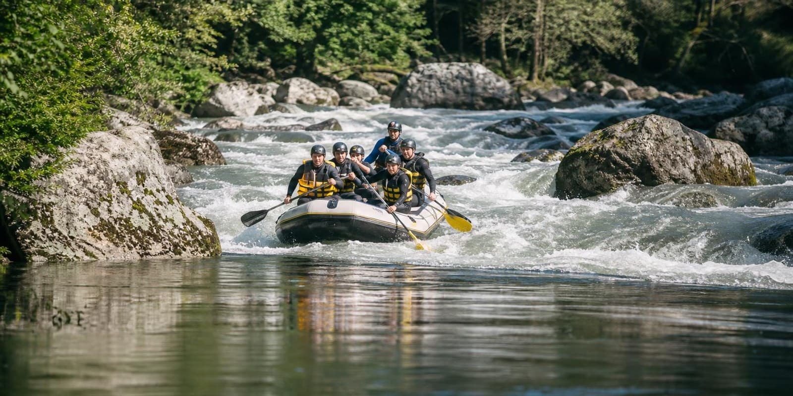 Fluss wechselt von ruhiger Stroemung zu tosender Stromschnelle, ein Raft sucht die Linie.