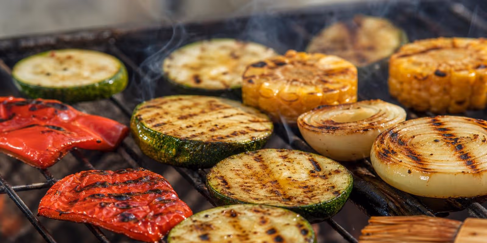 Buntes Gemuese mit Roestspuren brutzelt dicht an dicht auf dem Grillrost.