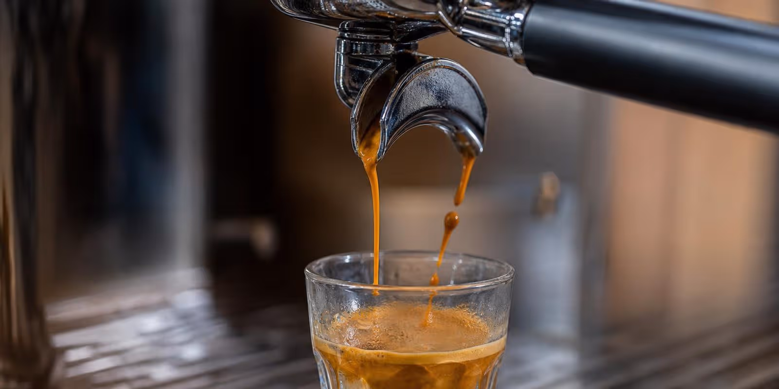 Espresso laeuft ungleichmaessig in ein Glas, die Crema ist blass und fleckig.