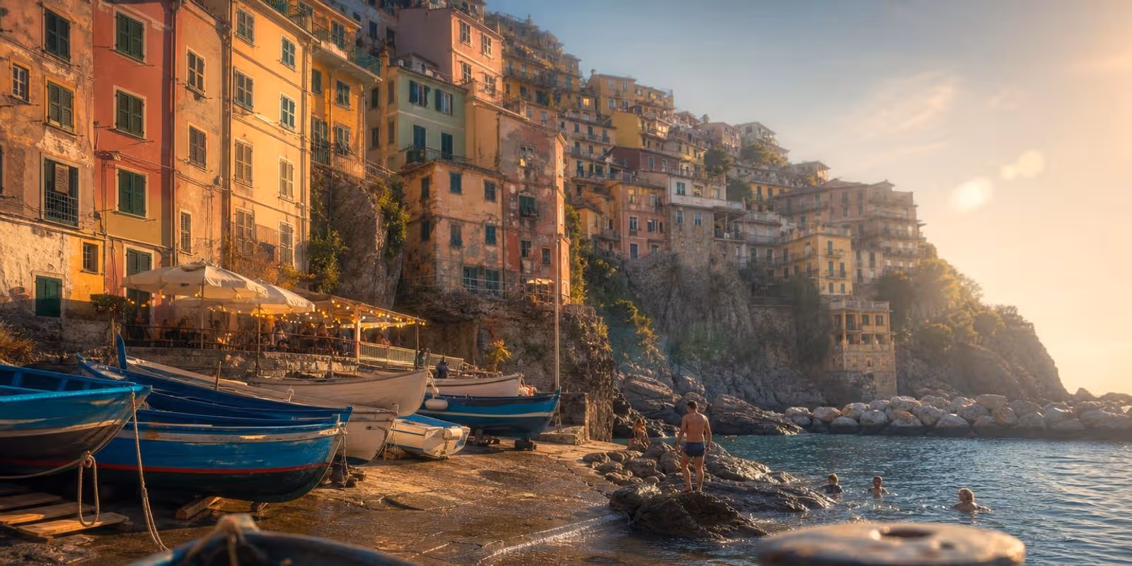 Kleiner Naturhafen eines Cinque-Terre-Dorfs mit bunten Haeusern und Fischerbooten.