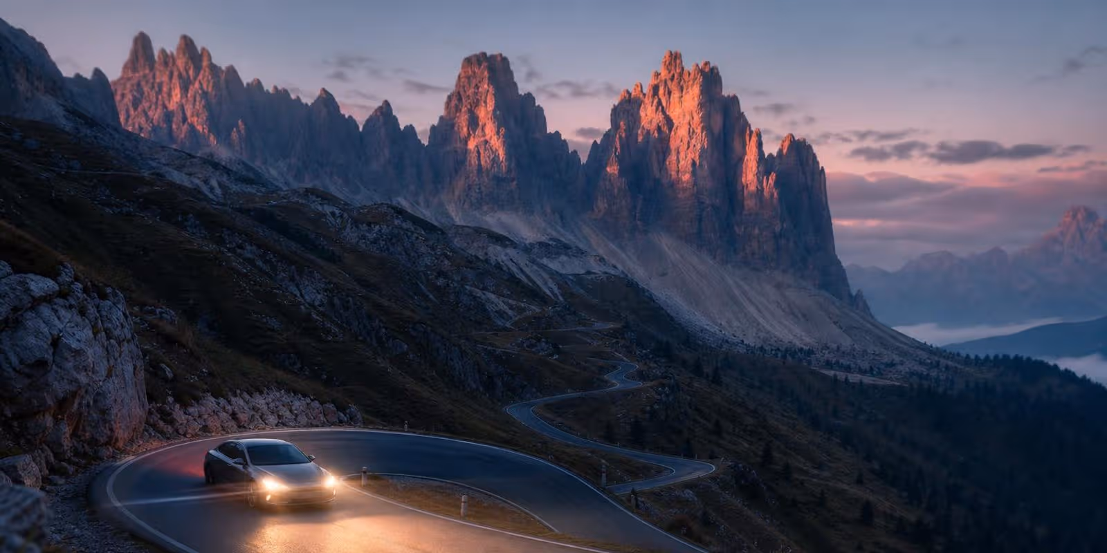 Serpentinenstrasse windet sich im Morgenlicht unter schroffen Dolomitengipfeln.