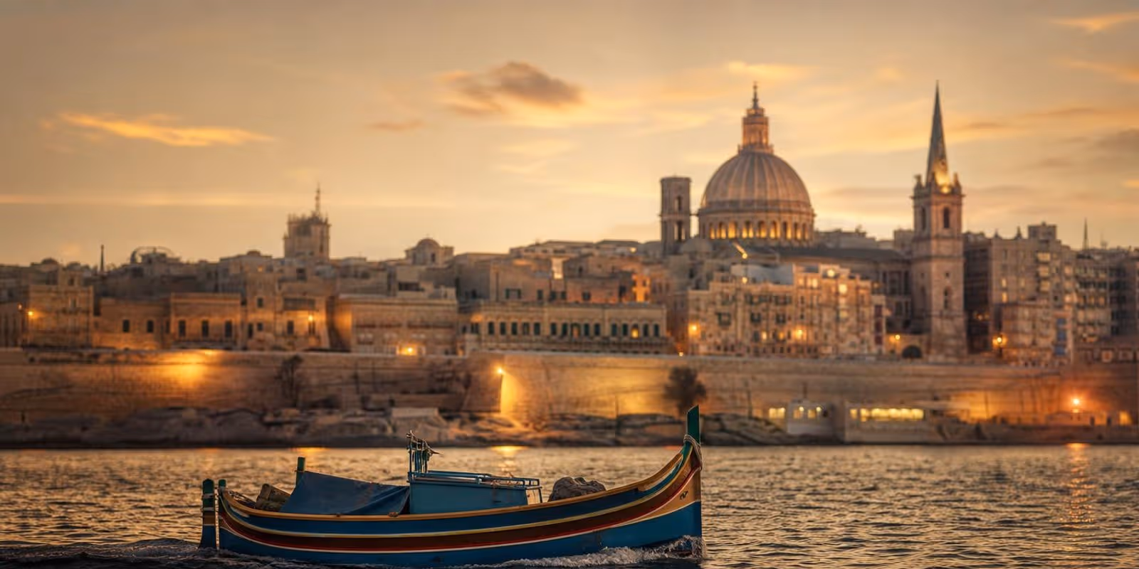 Festungsstadt Valletta leuchtet abends golden ueber dem Grand Harbour.